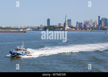 New York, USA - 26. August 2017: NYPD Boot patrouillieren East River. Im Hintergrund Blick auf die Freiheitsstatue und New Jersey Wolkenkratzer. Summe Stockfoto
