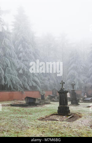 Geheimnisvolle belgischen Friedhof am Waldrand im Winter mit Frost, Eis und Schnee auf den Gräbern Stockfoto