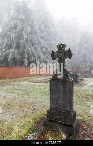 Geheimnisvolle belgischen Friedhof am Waldrand im Winter mit Frost, Eis und Schnee auf den Gräbern Stockfoto