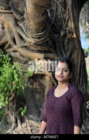 Schöne Bengali Mädchen steht vor einem großen Baum im Freien Stockfoto