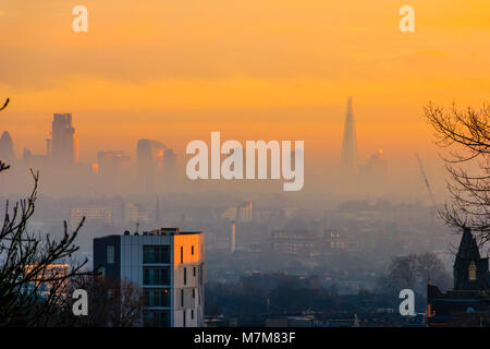 Eine orange Himmel über der Stadt London Skyline, durch Nebel und Umweltverschmutzung bei Sonnenuntergang verhüllt, von Hornsey Lane Bridge im Torbogen, nördlich von London, Großbritannien Stockfoto