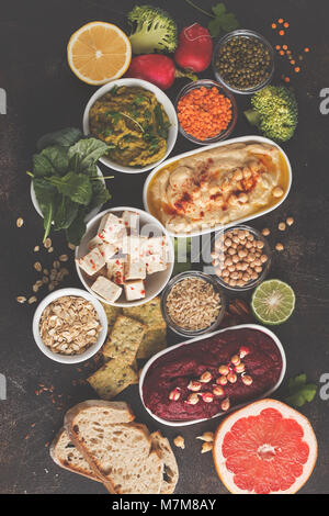 Veganes essen Hintergrund. Vegetarische Snacks: hummus Hummus, rote Beete, Erbsen dip, Gemüse, Tofu. Ansicht von oben, dunklen Hintergrund, kopieren. Stockfoto