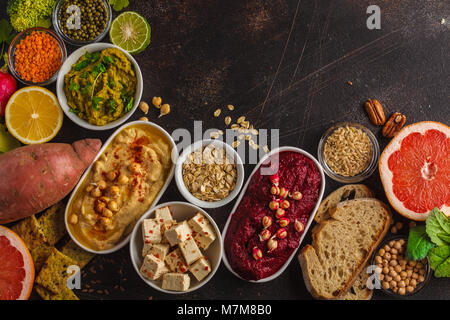 Veganes essen Hintergrund. Vegetarische Snacks: hummus Hummus, rote Beete, Erbsen dip, Gemüse, Tofu. Ansicht von oben, dunklen Hintergrund, kopieren. Stockfoto