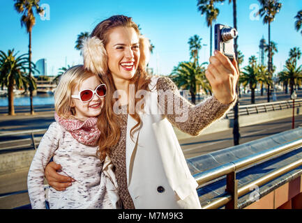 in Barcelona für einen perfekten Winter. glückliche trendige Mutter und Tochter Reisende auf Damm in Barcelona, Spanien mit Digitalkamera nehmen Foto Stockfoto