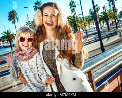 In Barcelona für einen perfekten Winter. Lächeln moderne Mutter und Tochter Reisende in Barcelona, Spanien handwaving Stockfoto