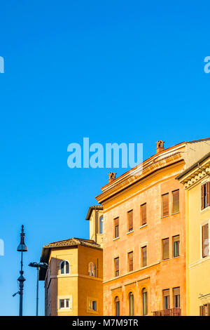Low Angle View Außenfassade typisch römische Wohnhäuser mit orange Farben gegen den blauen Himmel Hintergrund Stockfoto
