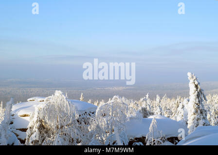 Winter Wald Landschaft an einem sonnigen frostigen Tag mit schneebedeckten Felsen im Vordergrund. Stockfoto