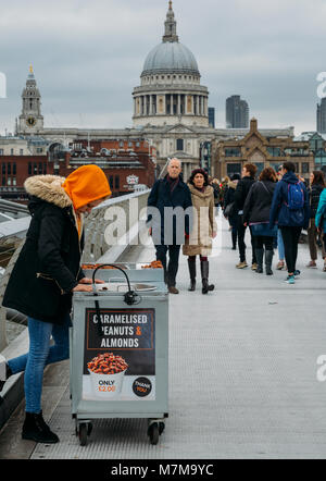 London, UK, 10. März 2018: junge Cameralised Erdnuss weibliche Verkäufer in der Londoner Millennium Bridge mit Blick auf die St. Paul's Cathedral Stockfoto