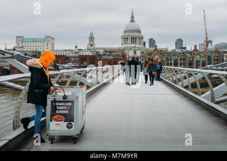 London, UK, 10. März 2018: junge Cameralised Erdnuss weibliche Verkäufer in der Londoner Millennium Bridge mit Blick auf die St. Paul's Cathedral Stockfoto