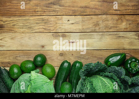 Bündel frischem organischen grünes Gemüse Wirsing Zucchini Gurken Paprika Avocados angeordnet im unteren Rand auf der Plank Holz zurück Stockfoto