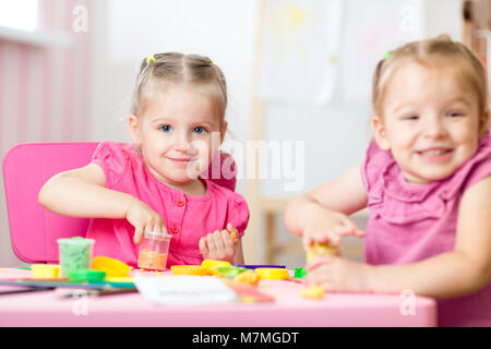 Zwei süße Vorschüler Schwestern Spaß zusammen mit bunte Knetmasse in eine Kindertagesstätte. Kreative Kinder Spritzgießen in Kindergärten zu Hause. Kinder spielen mit Plastilin oder Teig. Stockfoto