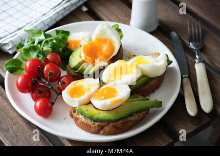 Ei und Avocado, grüner Salat und Kirschtomaten auf weiße Platte. Gesundes Frühstück, gesunde Lebensweise, vegan, vegetarisch oder Gewichtsverlust Konzept Stockfoto