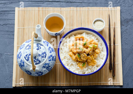 Chinesische Hühnchen mit Reis, Essstäbchen und grünen Tee auf Bambus Blatt. Traditionelle asiatische Küche Stockfoto