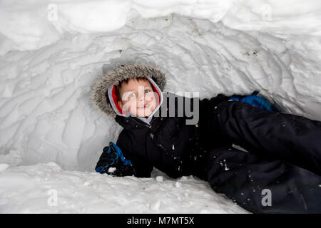 5 Jahre alter Junge spielt in seinem Iglu, Großbritannien Stockfoto