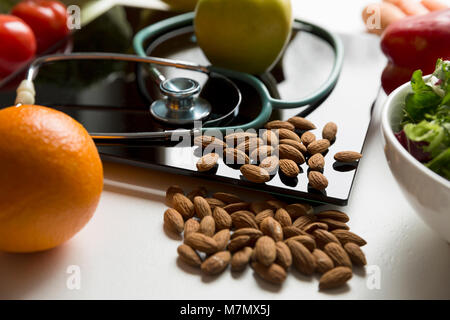 Gesundes Obst, Gemüse und Stethoskop auf Skalen. Gewicht Verlust und richtige Ernährung Konzept Stockfoto