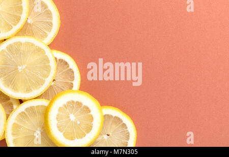 Scheiben Zitrone auf Lachs farbigen Hintergrund Stockfoto