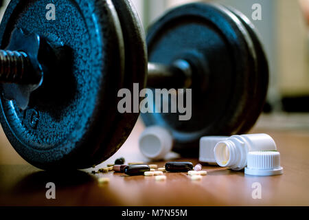 Steroid Pillen und Kapseln mit hantel Gewicht im Hintergrund - Doping im Sport. Stockfoto