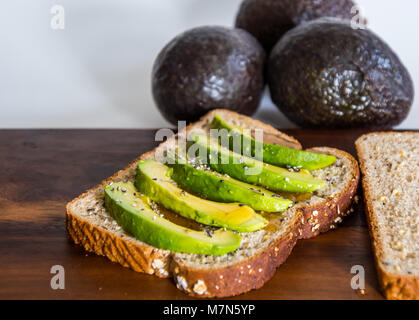 Scheiben der reife Avocado auf Vollkorn Toast Beträufelt mit Honig Stockfoto