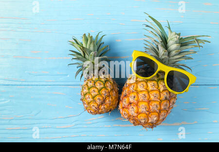 Ananas mit Sonnenbrille auf blauem Hintergrund Holz, Sommer Früchte Konzept Stockfoto
