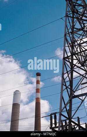 Zwei Schornsteine im industriellen Bereich neben Stromleitungen unter einer hübschen Sky Stockfoto