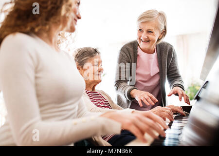 Ein Mädchen mit Mutter und Großmutter Klavier spielen. Stockfoto