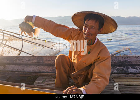 Intha Bein rudernden Fischer holding Fische am Inle See, Shan Staat, Myanmar (Birma), Asien im Februar - Fischer holding Fisch Stockfoto