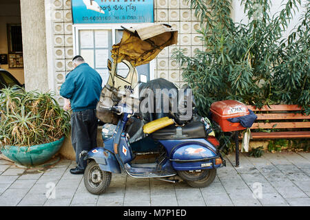 Alte jüdische Mann mit einem Moped mit einem hausgemachten Regenschutz geändert Stockfoto