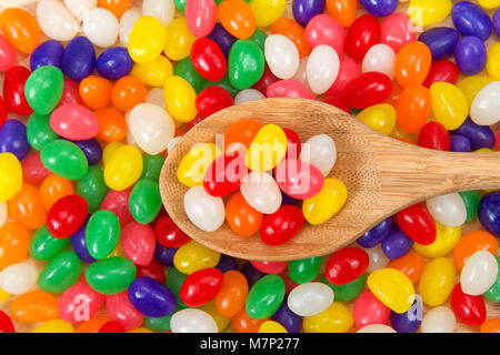 Viele Bunte Jelly Beans in einem Regenbogen an Farben. Beliebte Süßigkeit für Ostern. holzlöffel auf Stapel mit verschiedenen farbigen Candy innen Stockfoto