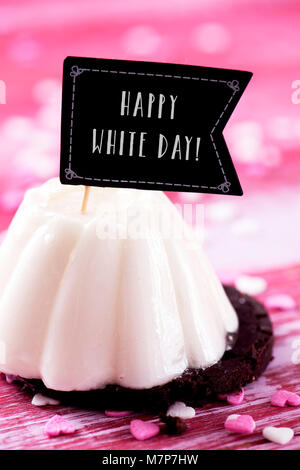 Eine weiße Kuchen gekrönt mit einem Flag-förmiges Schild mit dem Text happy White Day geschrieben, die beliebte asiatische Festlichkeit durch Frauen beobachtet, die Stockfoto