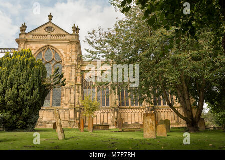 Alt und abgenutzt Stein Grabsteine auf dem Friedhof der St.-Mary's-Kirche in Warwick, Warwickshire mit den wichtigsten Teil der Kirche in den Boden zurück. Stockfoto