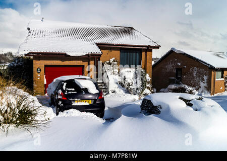 Auto eingeschneit auf einer Fahrstraße nach einem schweren Schnee, Erskine, Schottland. Stockfoto