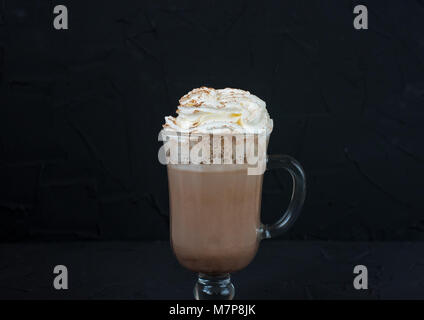 Glas Tasse mit Kakao und Sahne auf schwarzem Hintergrund. Stockfoto