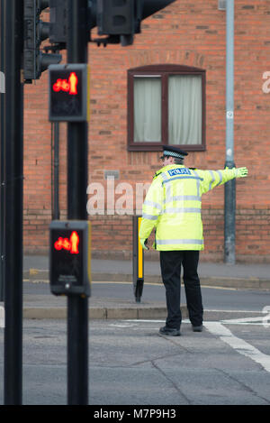 Polizist stand vor der Ampel leitet den Verkehr mit dem Bau- und Fenster im Hintergrund. Stockfoto