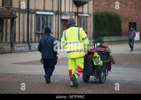 Street Sweeper geht weg drücken Ref und grau Barrow mit dem Gebäude im Hintergrund Stockfoto