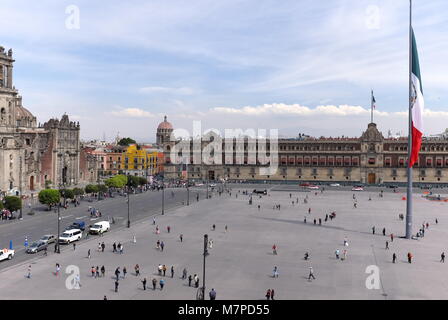 Die Nationalflagge von Mexiko Wellen über dem zocalo in Mexico City, einer der größten öffentlichen Plätze der Welt, umgeben von historischer Architektur. Stockfoto