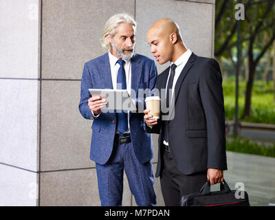 Kaukasische und Latino Führungskräfte diskutieren Unternehmen auf dem Weg zur Arbeit. Stockfoto