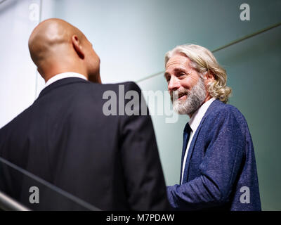 Kaukasische und Latino Führungskräfte reden Chatten während aufsteigende Treppen in modernes Gebäude. Stockfoto