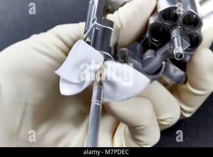 Hand einfügen Reinigung Stange mit einem Baumwolle Patch in den Lauf von snubnose Revolver auf einem schwarzen Matte isoliert Stockfoto