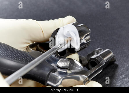 Hand einfügen Reinigung Stange mit einem Baumwolle Patch in die Kammer eines snubnose Revolver auf einem schwarzen Matte isoliert Stockfoto