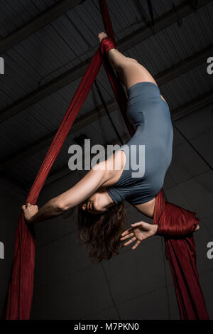 Anmutige Antenne Tänzer Frau Training mit roten Stoffen im Circus Stockfoto