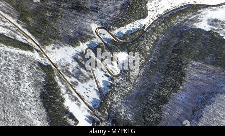 Antenne Landschaft mit vielen Bäumen und schlängelnde Mountain Road mit Autos und Lastwagen im Winter. Stockfoto