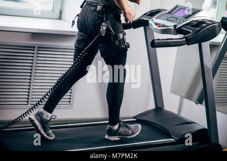 In der Nähe der Beine des Menschen in schwarzen Anzug electromiostimulation auf Laufband in der Nähe der Fenster Stockfoto