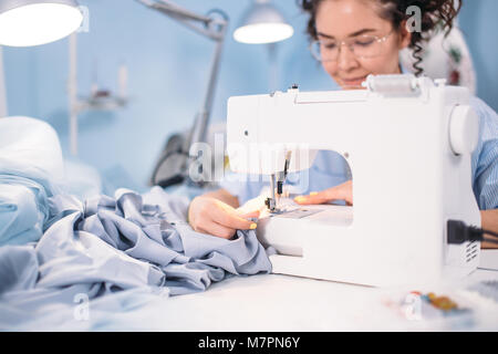 7/8 Schuß von Frau lernen auf der Nähmaschine in Design Studio zu nähen. Gehen in den Unterricht des Nähens. Hobby. Freie Zeit Stockfoto