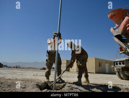 (Von links) der US Air Force Airman 1st Class Patrick Henry Alexander und Staff Sgt. William Thomas, 577Th Expeditionary Prime Base Engineer Emergency Force Squadron Truppe Konstruktionen, glätten Sie frisch gezapftes Zement am Flughafen Bagram, Afghanistan Mai 24, 2014. Mitglieder aus dem Geschwader, gegossen Betonpfosten für einen neuen Sicherheitszaun rund um den Flugplatz zu sichern. Die 577Th EPBS vereint Tiefbau Flieger aus ganz verschiedenen Spezialitäten freuen bereitgestellt Bauarbeiten durchzuführen. Henry Alexander ist von Davis Monthan, Ariz und ein Eingeborener von Gainesville, Fla. Thomas bereitgestellt wird Stockfoto