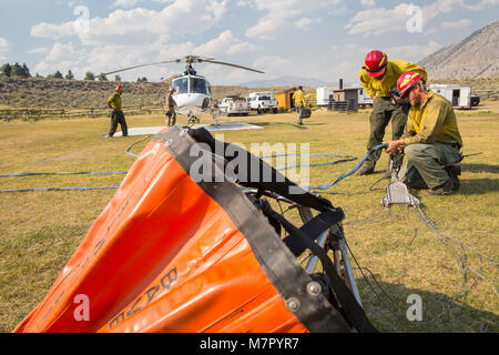 Helitack Besatzungsmitglieder rig einen Hubschrauber für Eimer tropfen Hubschrauber Wasser auf Brände Drop, um die Bewegungen zu kontrollieren oder löschen Ort Brände. Stockfoto