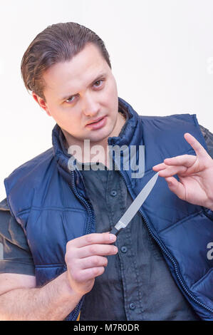 Porträt der jungen kaukasischen Ethnie mann Reinigung, seine Fingernägel mit Messer Stockfoto