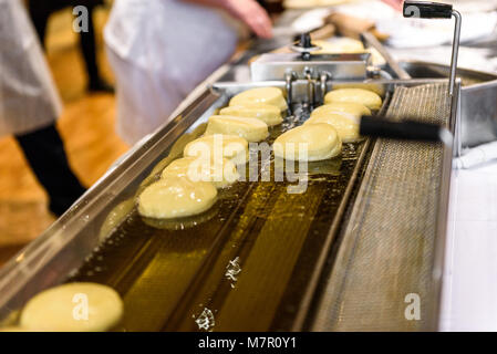 Die hausgemachte Marmelade Donuts in einem professionellen Restaurant Buffet Küche. Frittieren Donuts in heißem Öl im Restaurant Ofen oder Friteuse. Stockfoto