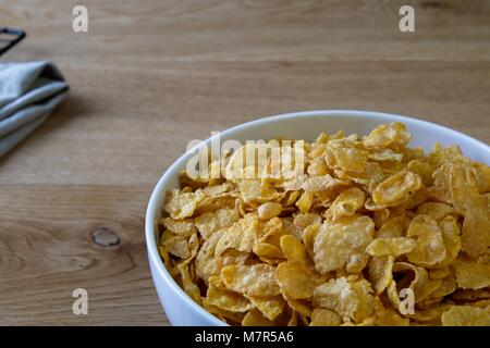Schüssel Cornflakes in Weiß Schüssel auf Eiche Oberfläche Nahaufnahme Stockfoto