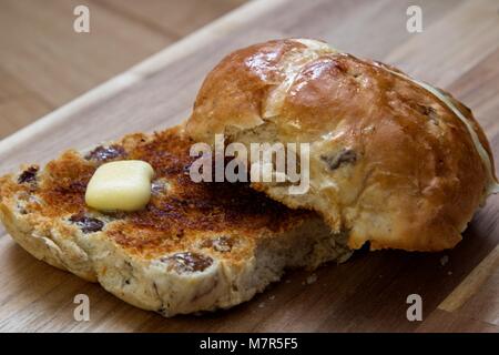 Seitenansicht des Hot Cross Brötchen mit Butter schmelzen auf Holz, das Board getoastet Stockfoto