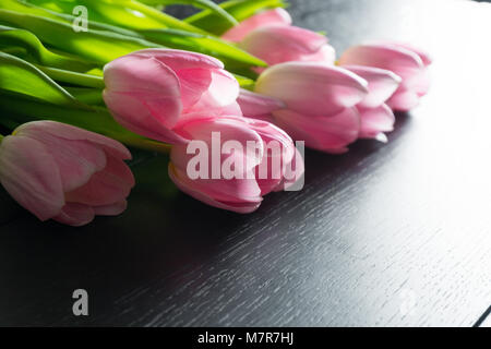 Grenze von hell rosa Tulpen Blumen auf schwarz Holz- Hintergrund. Stockfoto